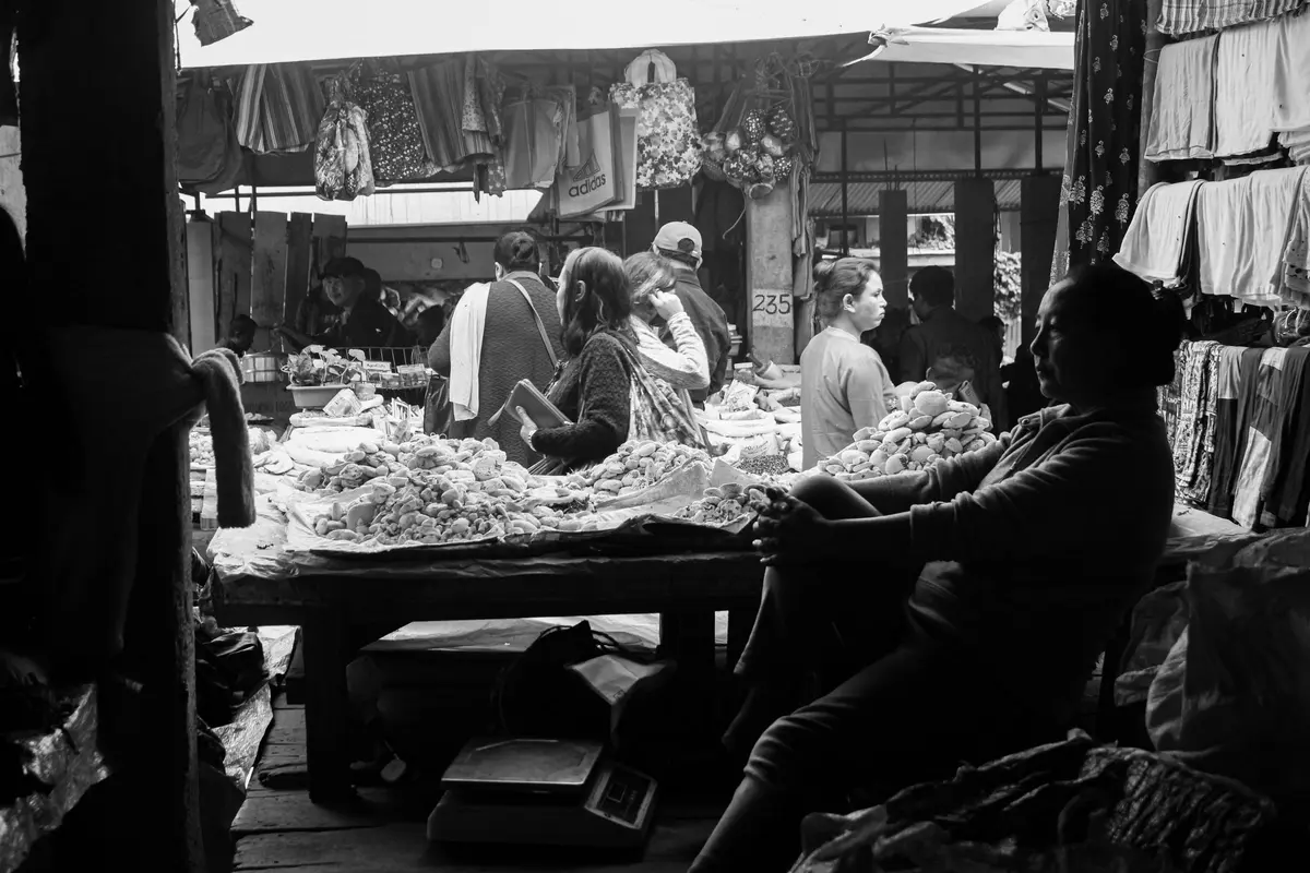 A bustling black and white market scene with vendors and customers.