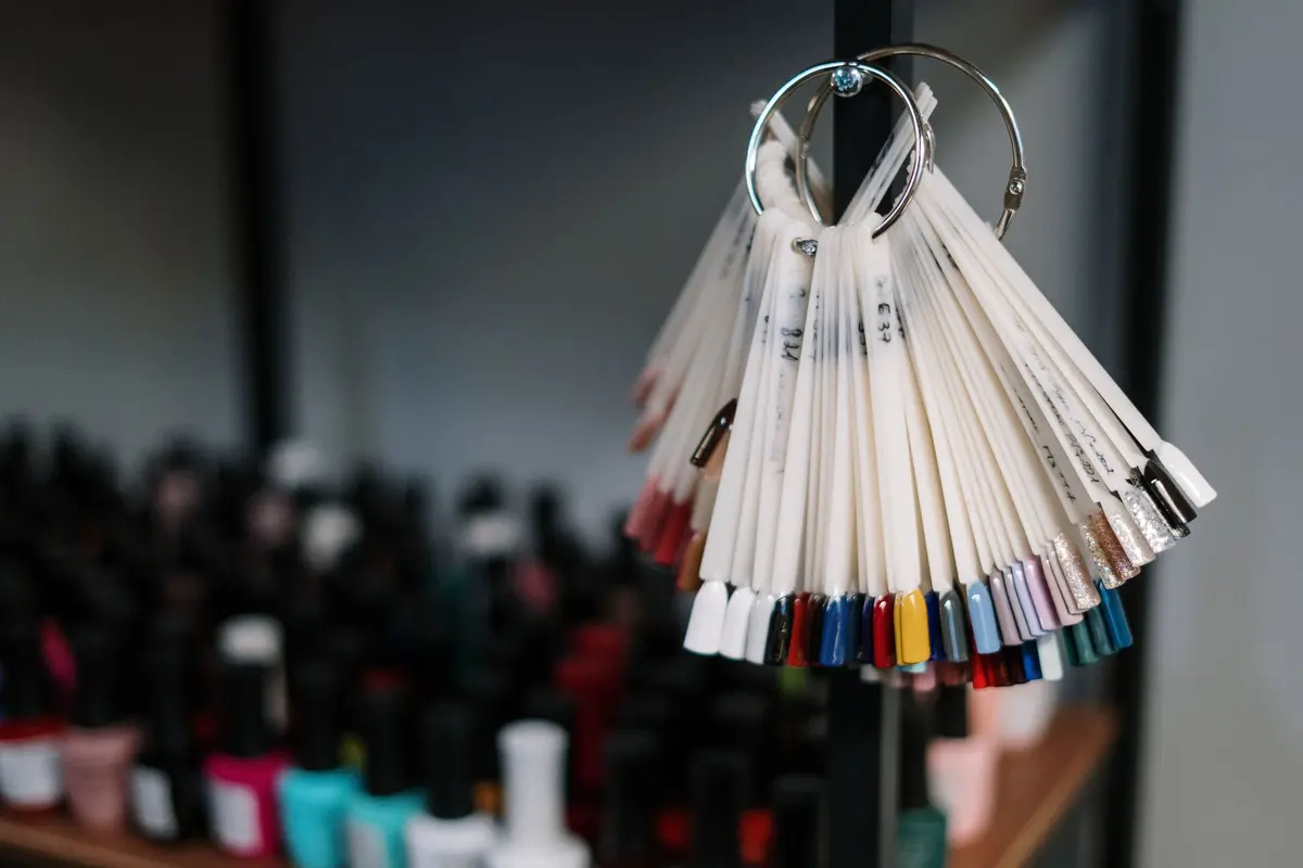 Colorful nail polish samples on display in a modern beauty salon, flanked by assorted bottles.